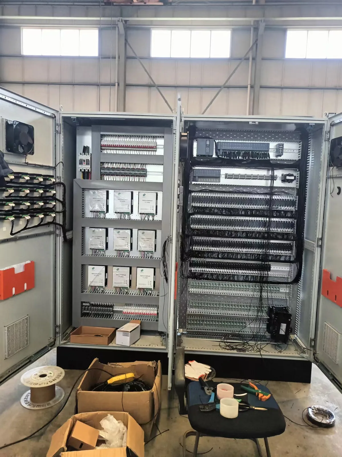 工人对照 PLC I/O 表接线：号码管、线槽、转角固定到位（车间实拍）